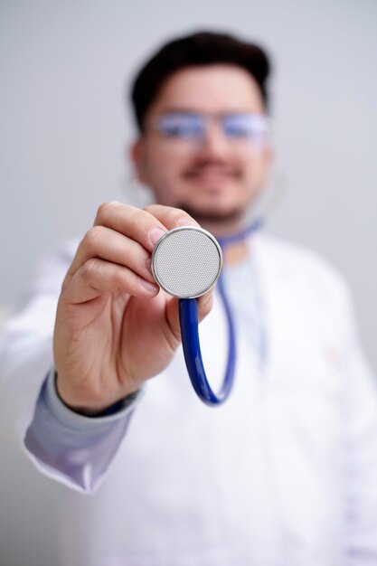 Foto um jovem médico está de pé e segurando o estetoscópio na mão e sorrindo