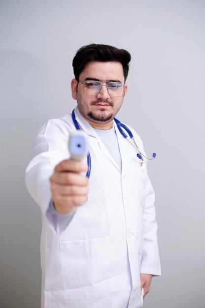 Foto um jovem médico está de pé e segurando o termômetro digital na mão