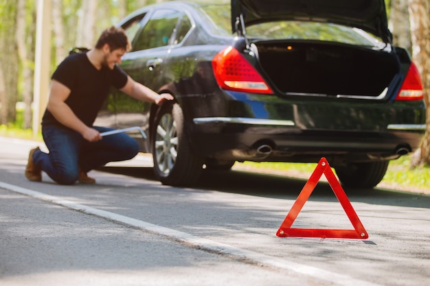 Um jovem motorista na estrada trocando uma roda