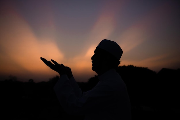 Um jovem muçulmano asiático rezando no conceito de festival do pôr do sol do Ramadã