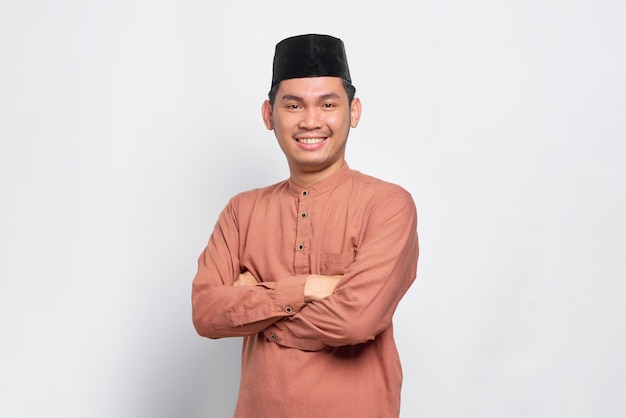 Um jovem muçulmano asiático sorridente cruzou os braços e parece confiante isolado sobre fundo branco