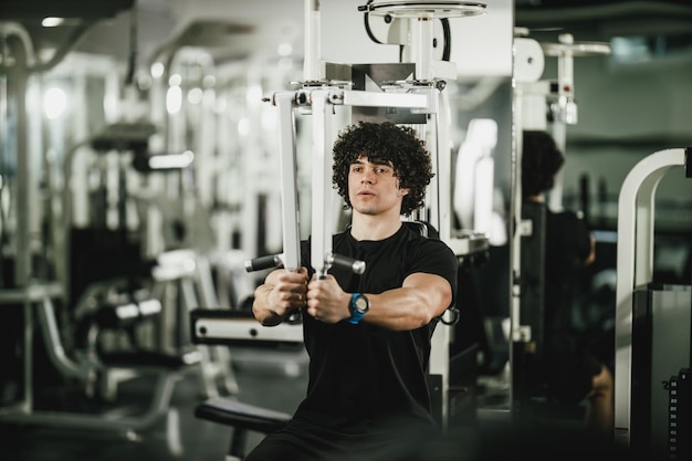 Um jovem musculoso está treinando na máquina no ginásio.