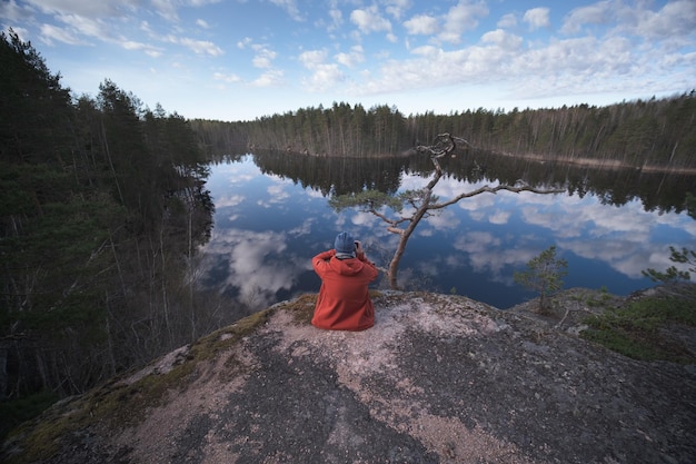 Um jovem na margem de um lago de floresta pitoresca de espelho Um homem fotografa uma paisagem pitoresca Vista traseira