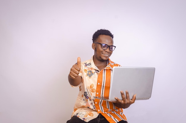 Foto um jovem negro animado sentado sorrindo segurando o laptop em suas mãos bate olhando para o laptop