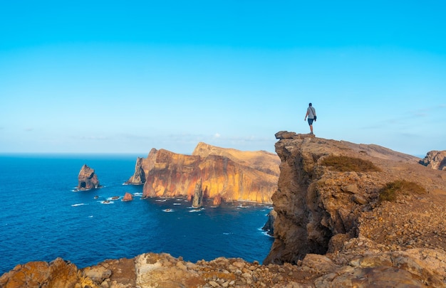 Um jovem num penhasco na Ponta de São Lourenço na costa com formações rochosas no verão Madeira