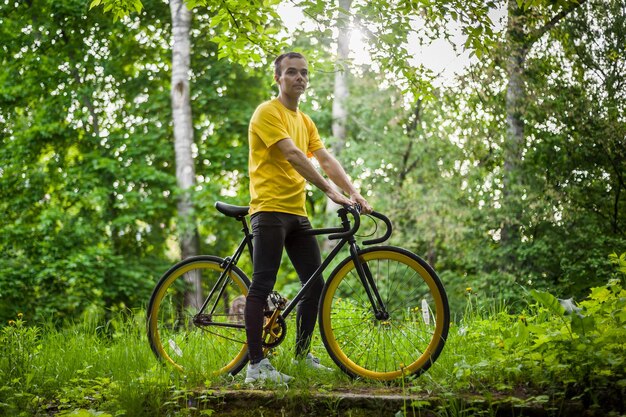 Um jovem parou para descansar com sua bicicleta em um parque público