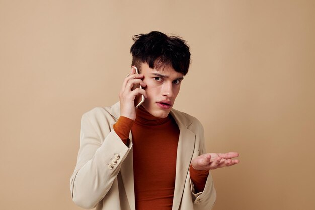 Um jovem posando com um telefone nas mãos em um estúdio de modelo de estilo elegante de jaqueta