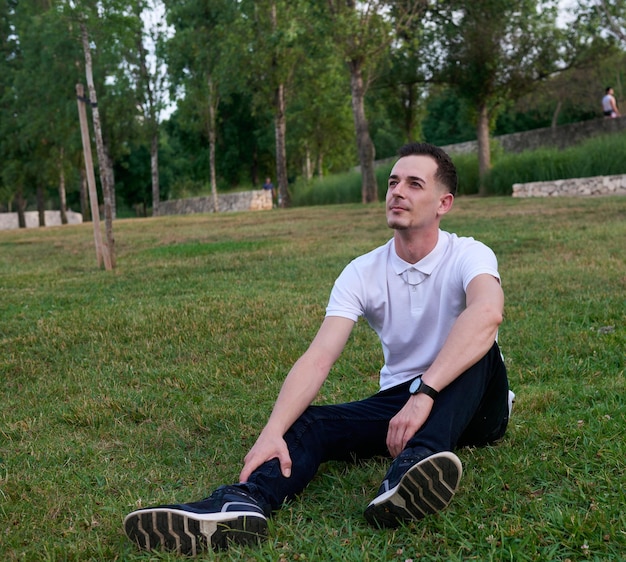 Um jovem posando relaxado na grama em um parque