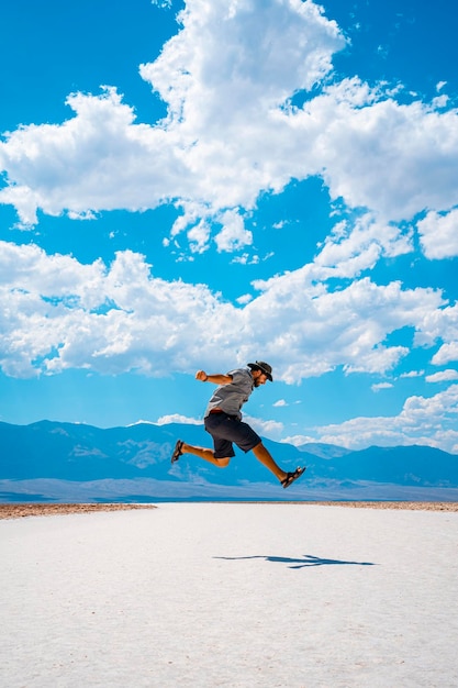 Um jovem pulando com uma camisa azul no sal branco de Badwater Basin Death Valley