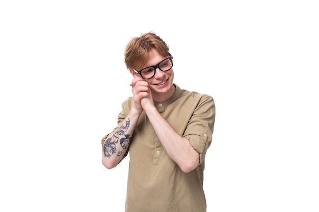 Um jovem ruivo inteligente com uma camisa bege usa óculos em um fundo branco