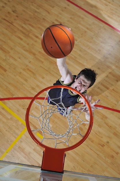 Um jovem saudável joga basquetebol no ginásio da escola.