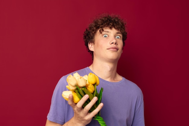 Um jovem segurando um buquê amarelo de flores camisetas roxas fundo isolado inalterado