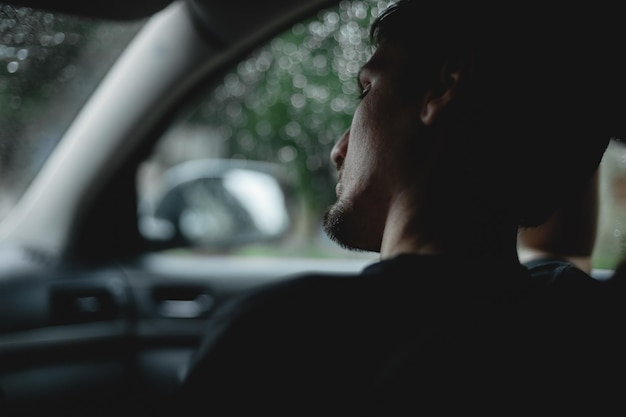 Um jovem senta-se pensativamente no carro