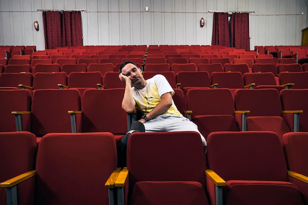 Um jovem solitário em um teatro vazio adormeceu na apresentação Um homem de ópera chato e desinteressante com óculos dormindo sozinho na sala de cinema enquanto todos estão fora