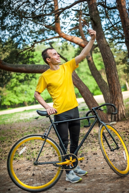 Um jovem tirando uma selfie com sua bicicleta