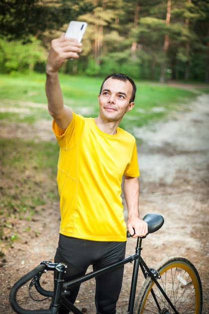 Um jovem tirando uma selfie com sua bicicleta