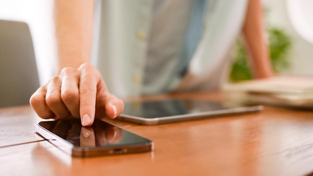 Um jovem tocando na tela do smartphone usando o celular nesta mesa Closeup dedo