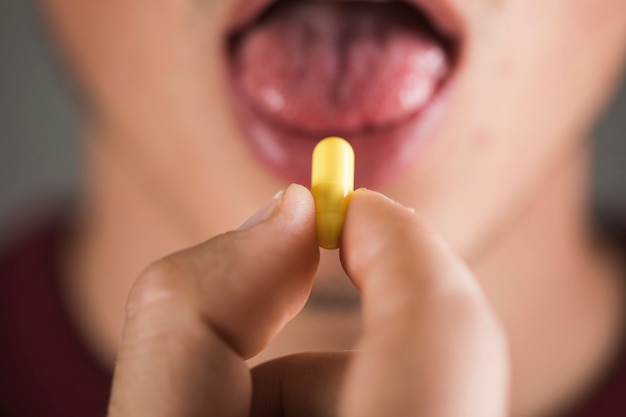 Um jovem toma uma pílula amarela