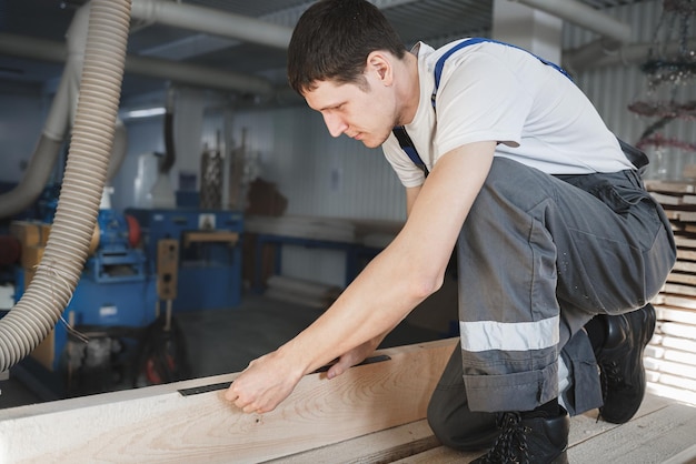 Um jovem trabalha em uma carpintaria Um funcionário mede madeira com uma régua