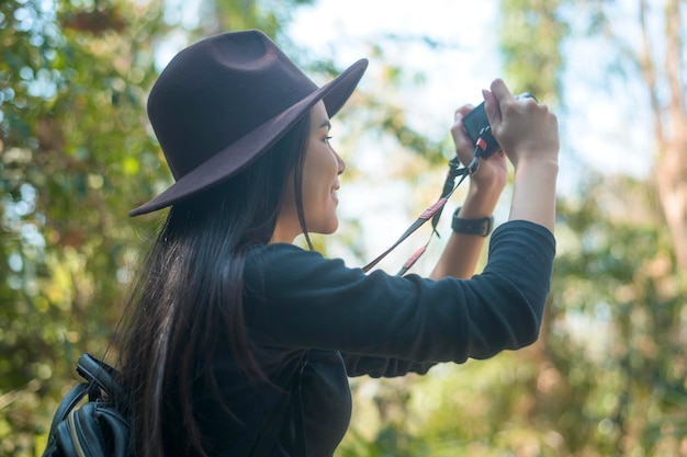 Um jovem trekker tirando fotos da natureza com câmera na floresta, férias e conceito de viagem.