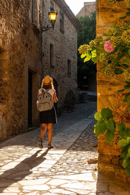 Um jovem turista andando nas ruas da cidade medieval de Pals do centro histórico ao pôr do sol