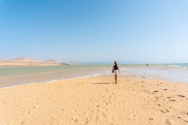 Um jovem turista caminhando ao longo da praia de sotavento em uma manhã de outono no sul de fuerteventura, nas ilhas canárias. espanha