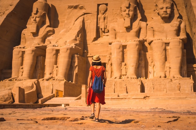 Um jovem turista em um vestido vermelho caminhando em direção a Abu Simbel