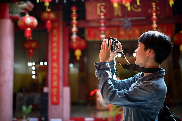 Um jovem turista feliz tirando fotos de um belo templo chinês com sua câmera