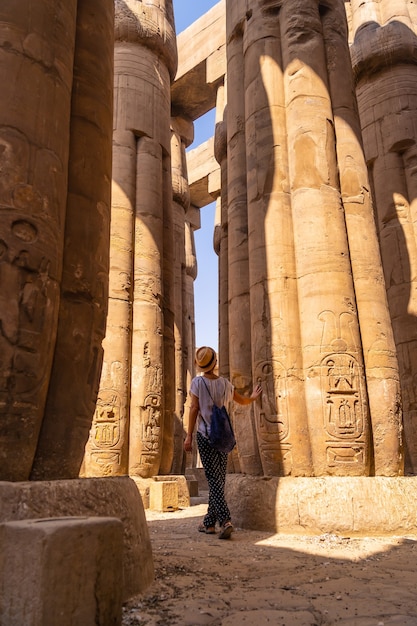 Um jovem turista olhando para os desenhos egípcios nas colunas do templo de luxor, egito