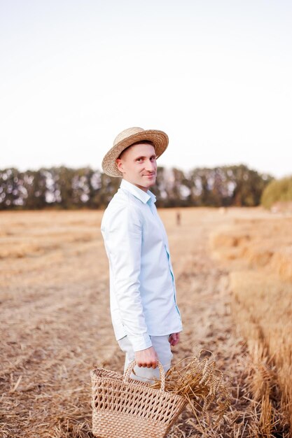 Um jovem ucraniano em um campo de trigo com um sorriso em um chapéu de palha Roupas masculinas elegantes de verão