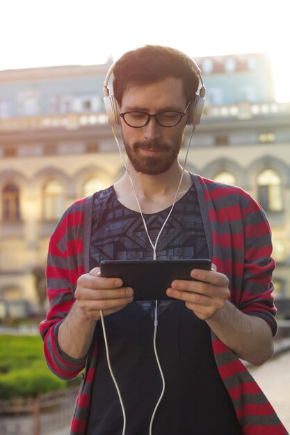 Foto um jovem usa um tablet ao ar livre.