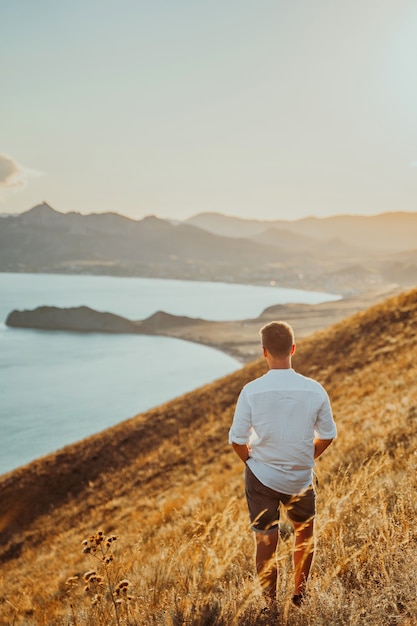 Um jovem viaja ao longo da costa da montanha ao pôr do sol Um homem está na encosta de uma montanha
