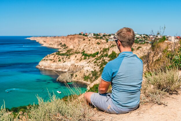 Um jovem viaja para o Cabo Fiolent, o lugar mais famoso da Crimeia com ondas azuis e rochas