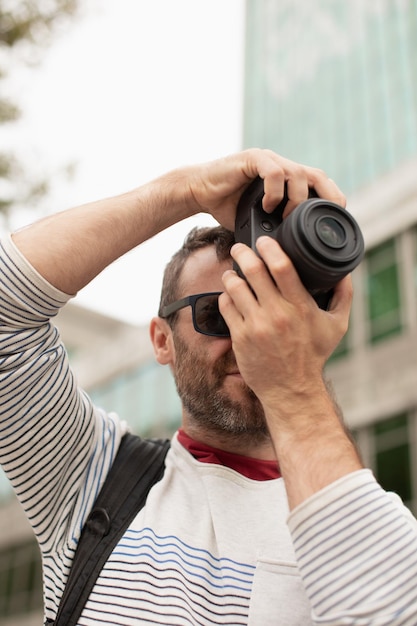 Um jovem viajante tirando fotos com uma câmera digital nas ruas de uma cidade na Espanha