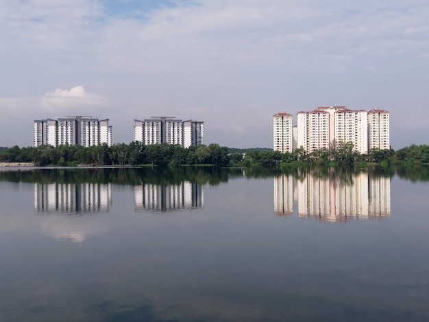 Foto um lago com alguns prédios altos e algumas árvores no lado esquerdo.