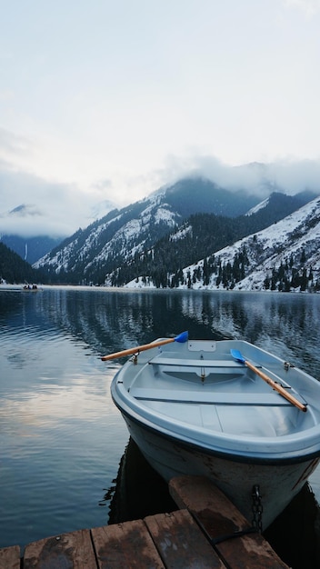 Um lago de montanha na floresta com água espelhada. Cais de madeira com barco branco.