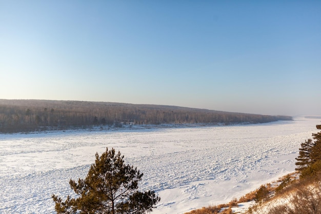 Um lago ou rio congelado no inverno. Perto da floresta e montanhas na neve. paisagens de inverno