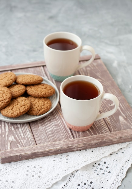 Um lanche saboroso: duas xícaras de chá e um prato de biscoitos.