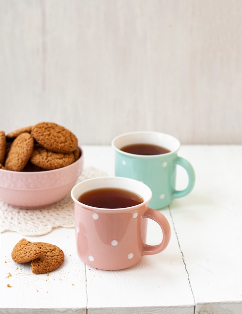 Um lanche saboroso: duas xícaras de chá e uma tigela de biscoitos.