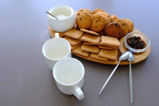 Um lanche saboroso duas xícaras de chá preto e um prato de biscoitos de aveia uma placa de madeira no chá de folha de fundo cinza