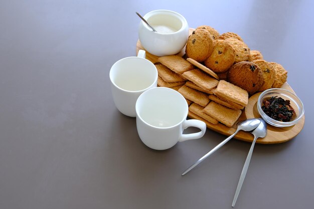 Um lanche saboroso duas xícaras de chá preto e um prato de biscoitos de aveia uma placa de madeira no chá de folha de fundo cinza