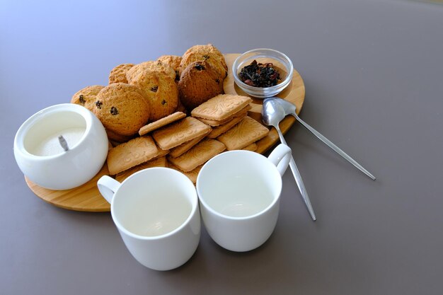 Um lanche saboroso duas xícaras de chá preto e um prato de biscoitos de aveia uma placa de madeira no chá de folha de fundo cinza
