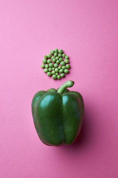 Um layout criativo feito de grãos de ervilha em forma de círculo e pimenta verde em um fundo rosa. vista do topo