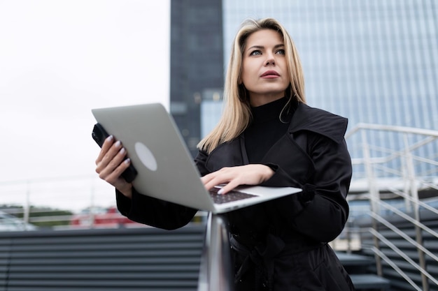 Um líder de sucesso está estudando um canteiro de obras na rua segurando um laptop nas mãos