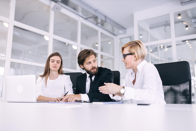 Um líder masculino sério com seus colegas senta-se à mesa e