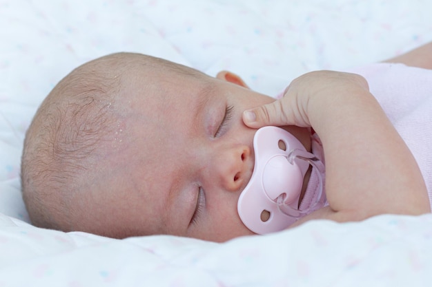 Foto um lindo bebê recém-nascido com uma chupeta rosa na boca