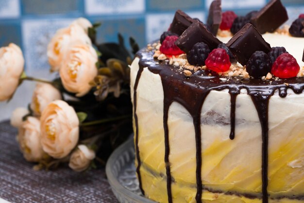 Foto um lindo bolo festivo com glasura de chocolate e geleia sobre um fundo de flores