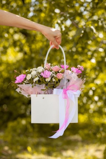 Um lindo buquê de flores em uma caixa nas mãos de uma linda garota em um fundo verde