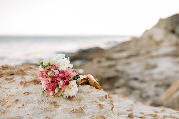 Um lindo buquê de flores repousa sobre uma pedra na praia