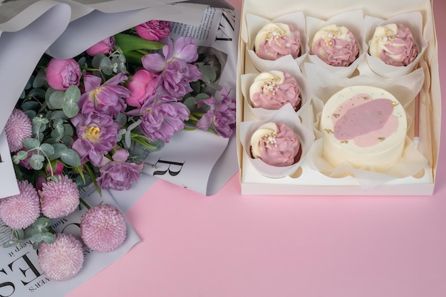 Um lindo buquê e cupcakes estão na mesa rosa